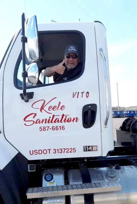 Keele Sanitation employee driving truck giving a thumbs up.